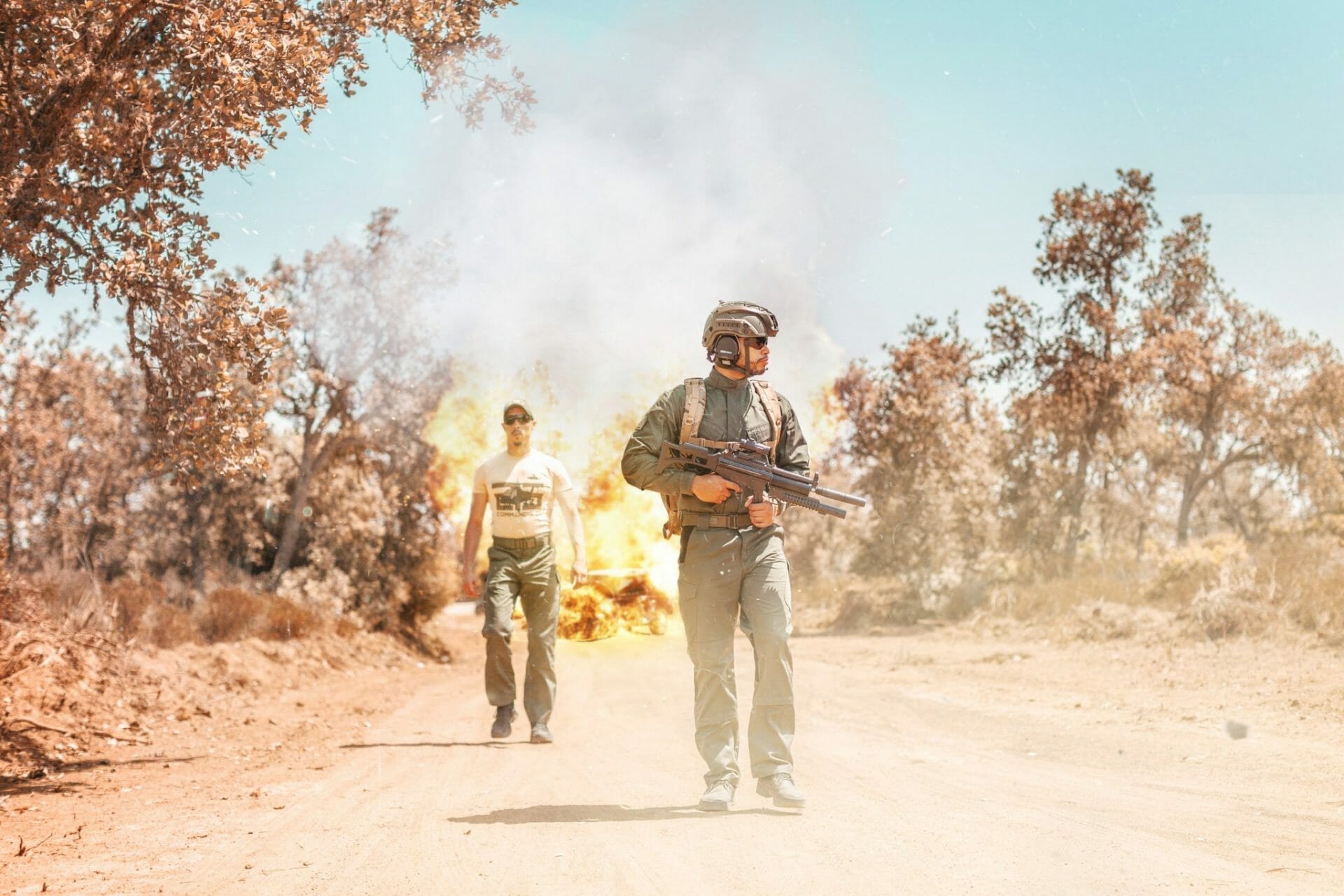Deux hommes debout sur un chemin de terre près d'un feu.