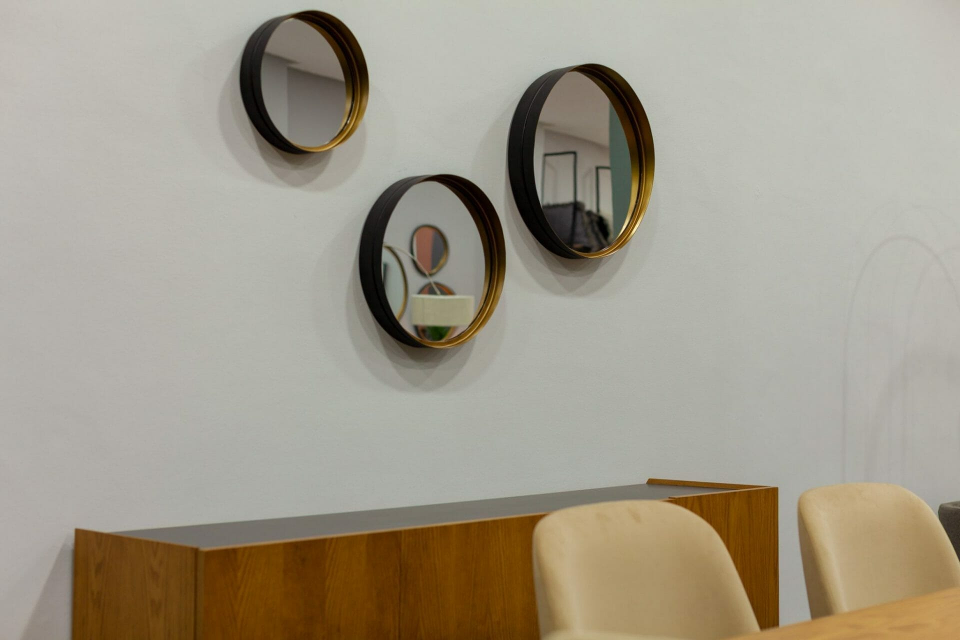 Trois miroirs ronds sur le mur d'une salle à manger.