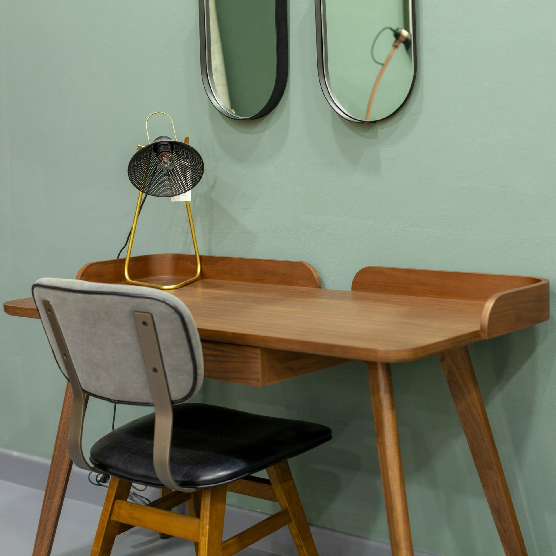 Un bureau avec une chaise et deux miroirs.