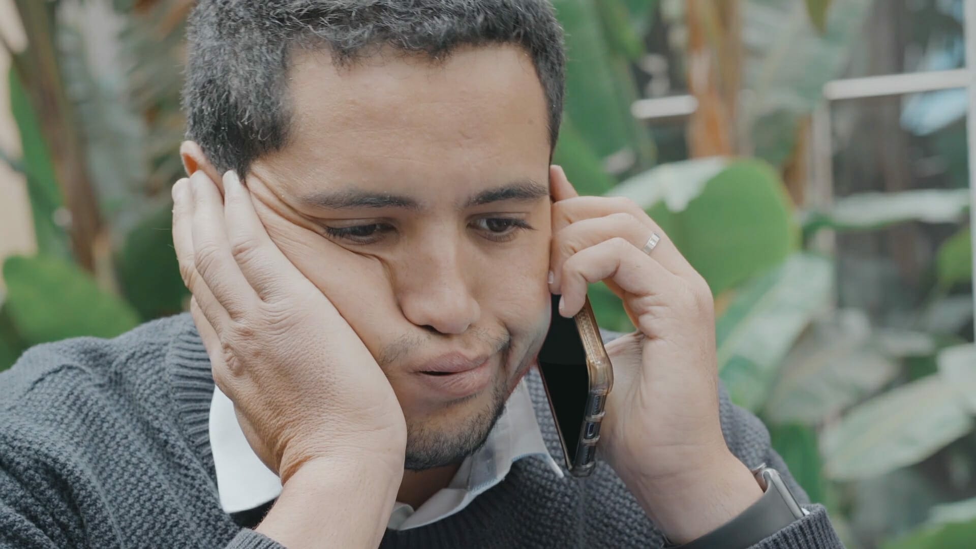 Un homme parle sur un téléphone portable avec sa main sur son visage.