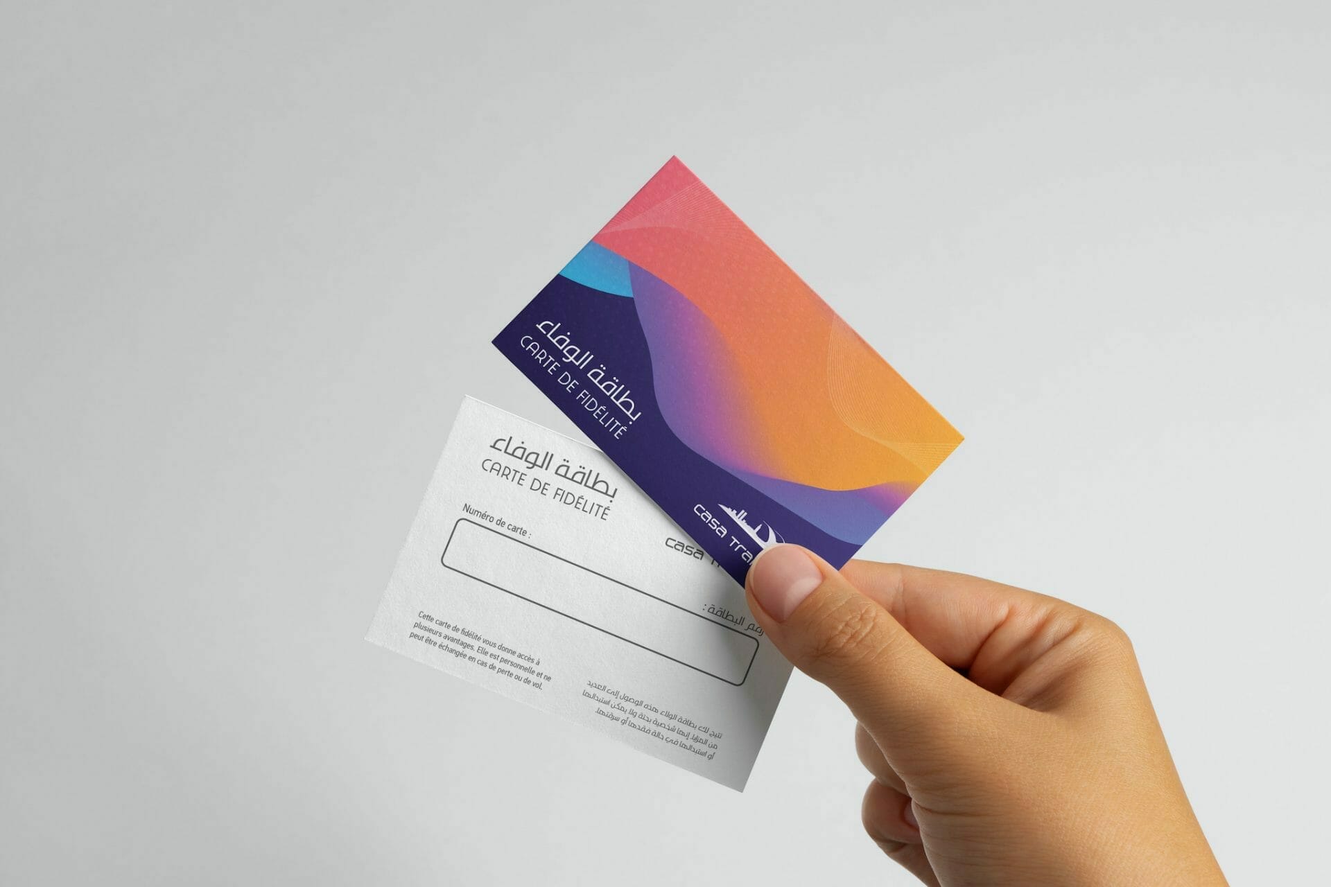 Une main tenant une carte de visite avec un fond coloré.